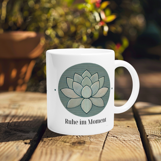 Weiße Tasse mit Lotusblume und dem Spruch „Ruhe im Moment“ – Symbol für Achtsamkeit